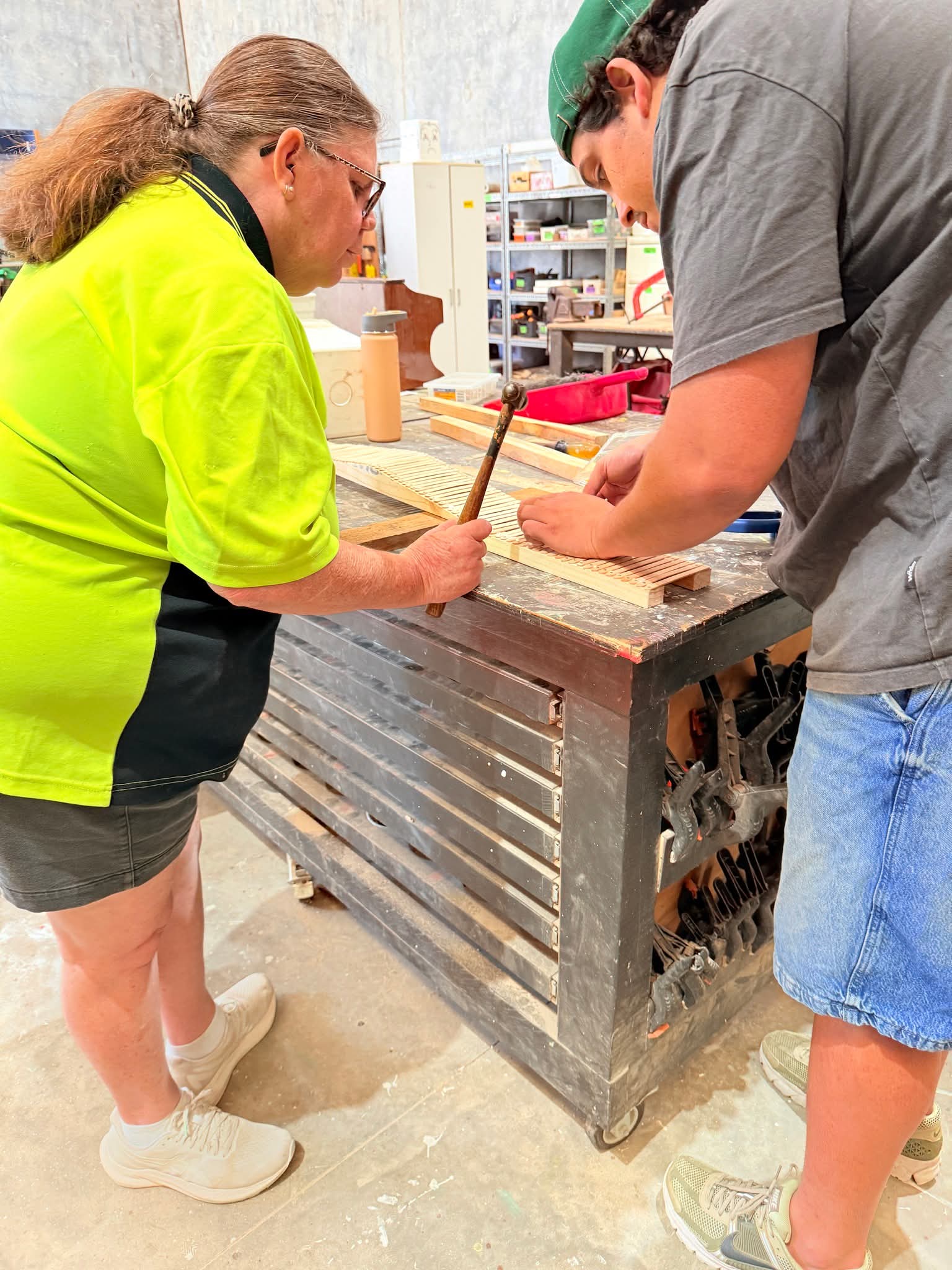 Coach supporting participant with a timber workshop activity